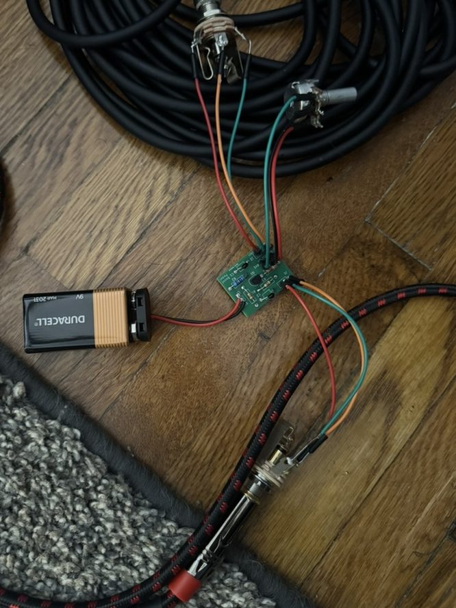 The fabricated boost pedal board populated and wired up, with the 9V battery, volume potentiometer, and input and output jacks soldered to its pin headers